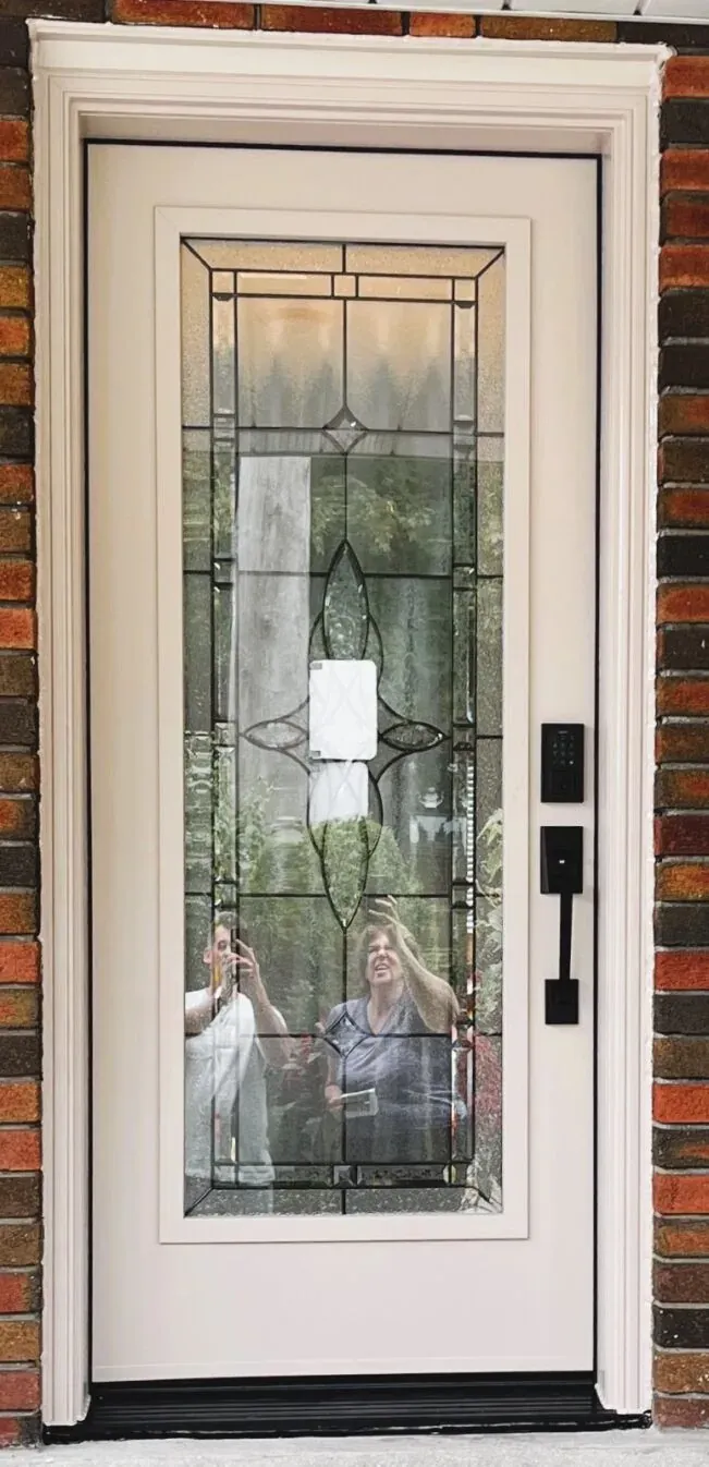 Cream entry door with leaded decorative glass and smart lock on a Burlington brick home